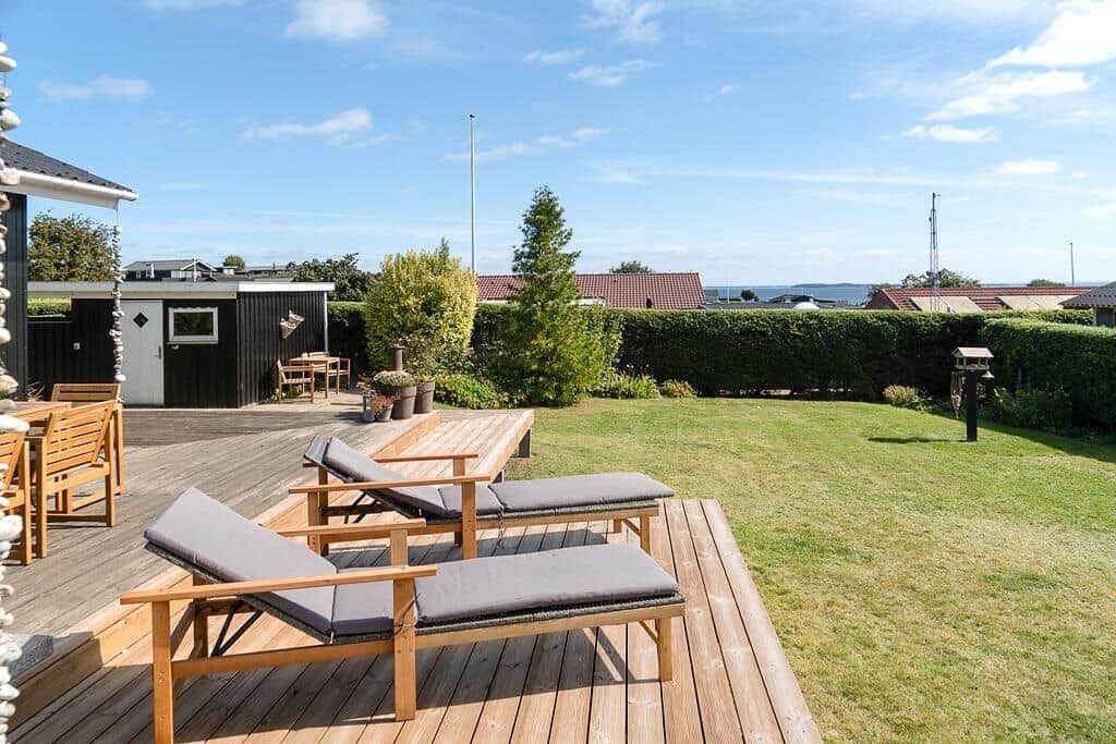 Terrasse mit Liegestühlen und Blick auf den Garten und die Ferne.