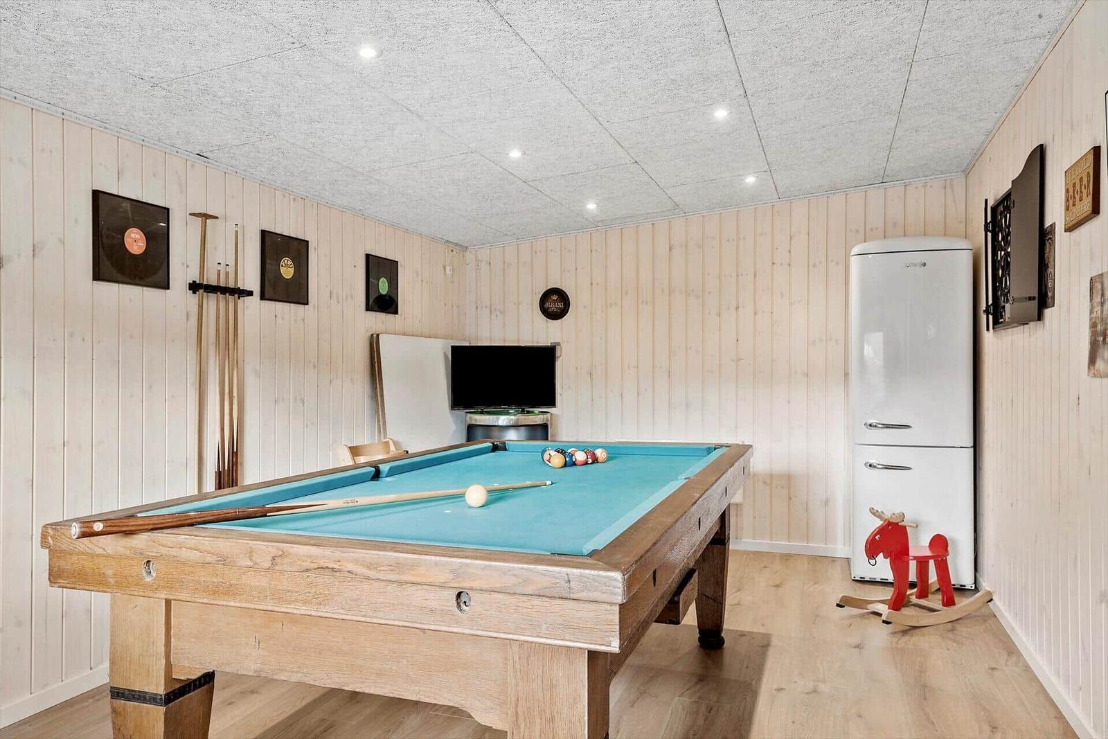 Raum mit Billardtisch, Kühlschrank und Fernseher an der Wand.