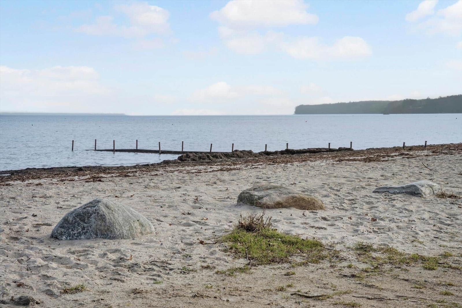 Strand mit Steinen und ruhigem Wasser im Hintergrund.