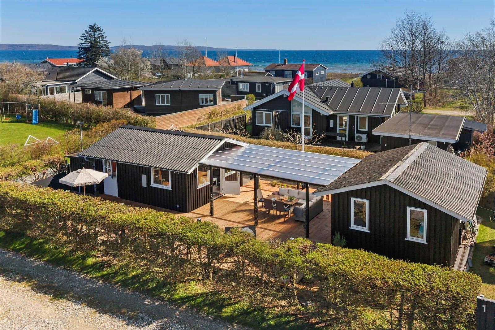 Haus mit Terrasse und Garten, Blick auf Meer und Flagge. Holzhaus mit moderner Veranda.