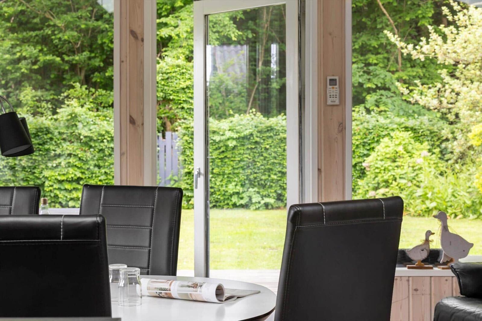 Essbereich mit schwarzen Stühlen und Blick auf grünen Garten