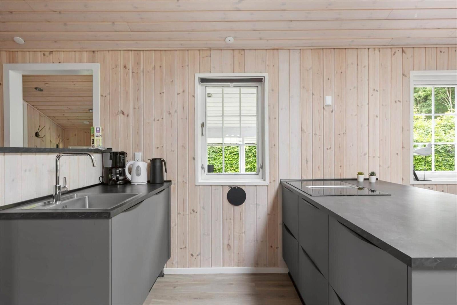 Küche mit Holzwänden, Arbeitsplatte und Fenster. Küche mit modernen Geräten.