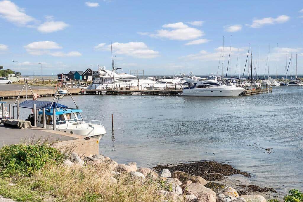 Hafen mit Booten und kleinem Steg. Hintergrund: Segelboote und Yachten.