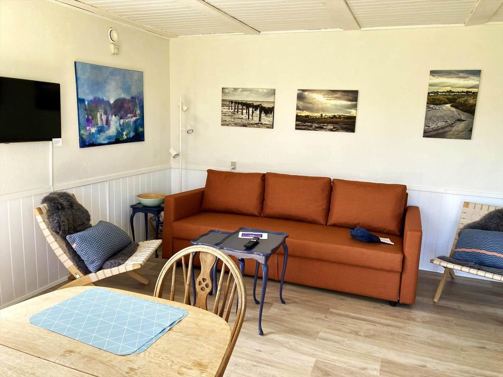 Living room with orange sofa, two chairs, and wall art.
