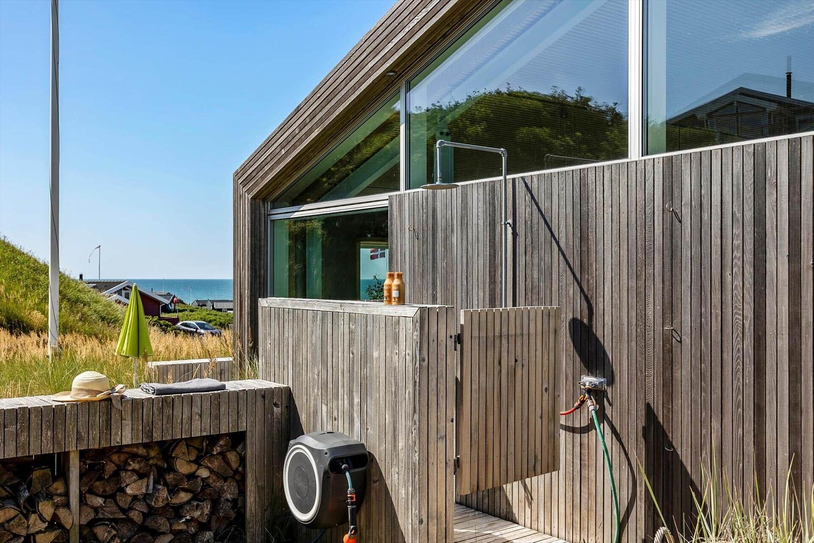 Außenbereich mit Dusche, Holzverkleidung und Blick aufs Meer.