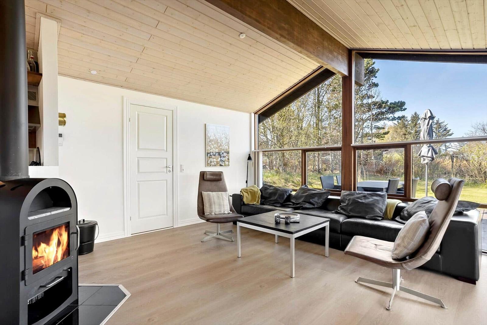 Wohnraum mit Kamin, Sofa und großem Fensterblick auf Garten