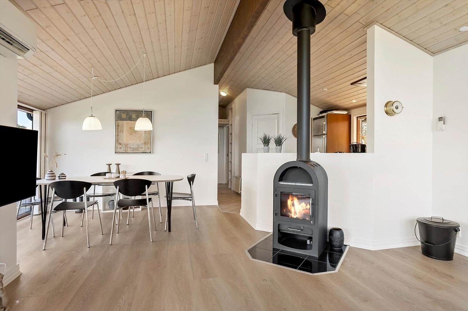 Wohnraum mit Esstisch, Kamin und Holzdecke.