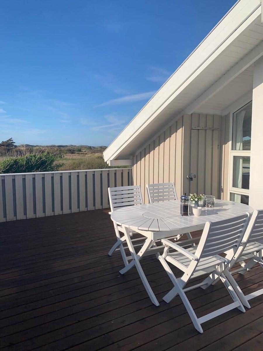 Terrasse mit weißem Tisch und Stühlen, Blick auf die Landschaft.