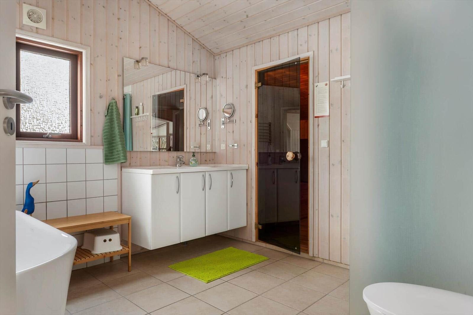 Badezimmer mit Holzwand, Waschbecken, Dusche und Badewanne.