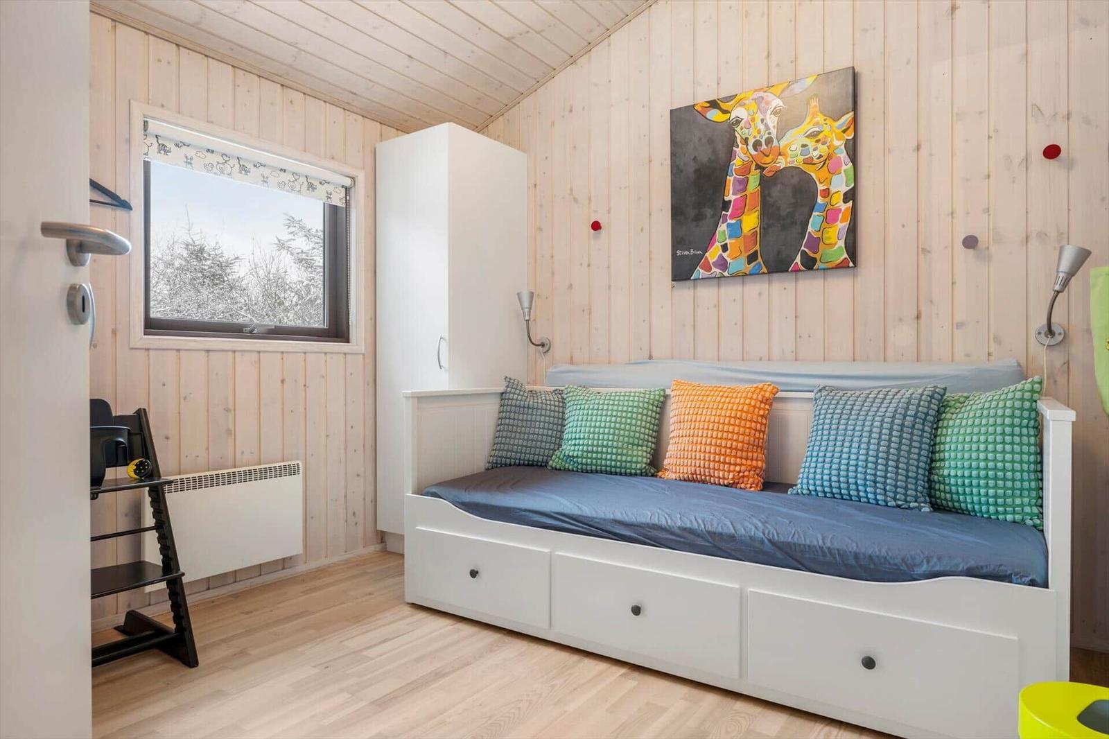 Schlafzimmer mit Bett, Wandbild und Fenster. Holzwände und Boden.