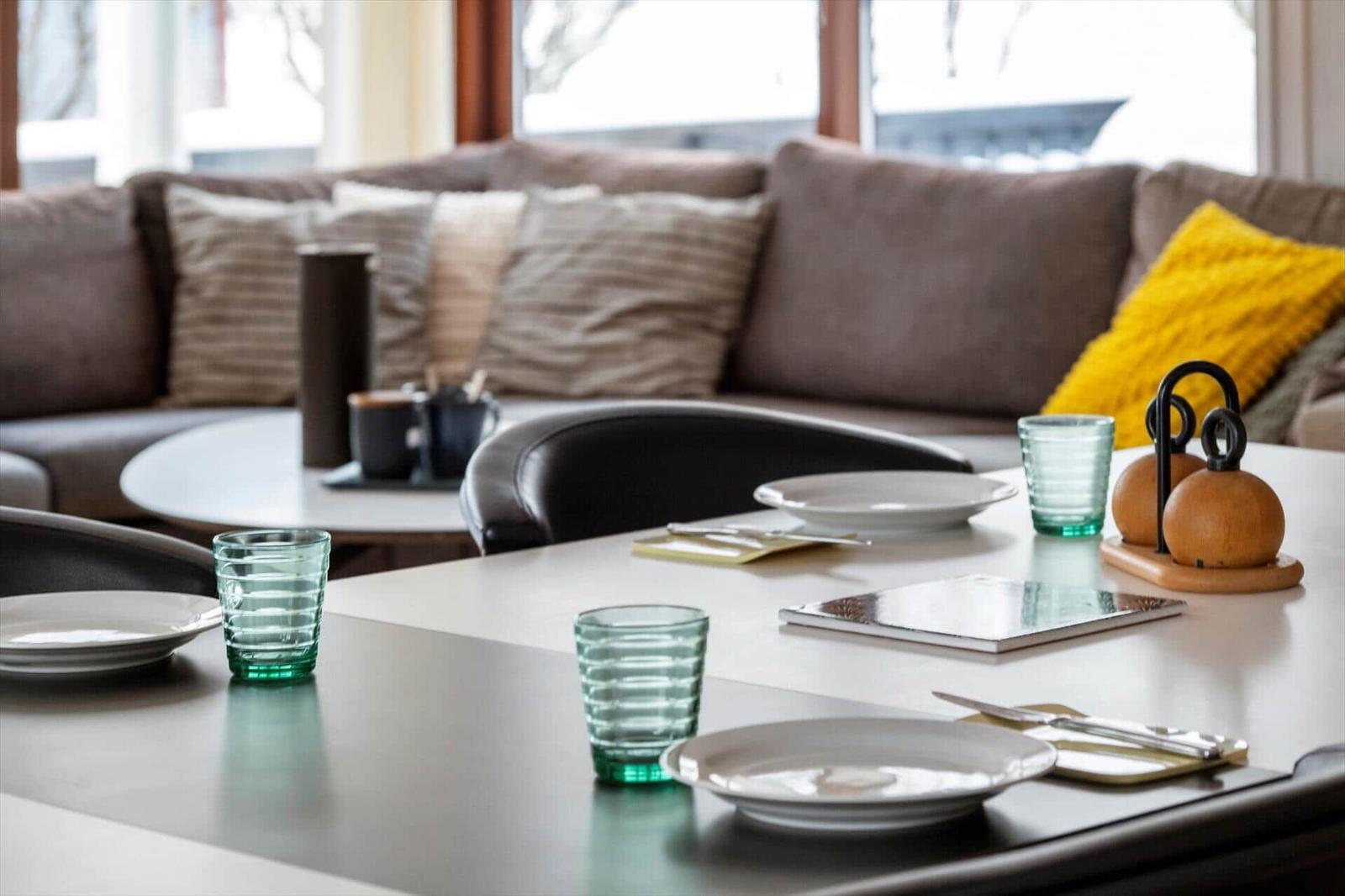 Esstisch mit Tellern und Gläsern. Hintergrund: Sofa mit Kissen.