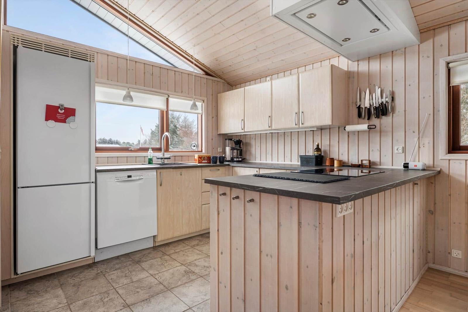 Küche mit Holzwand, Kücheninsel und Fenster mit Blick nach draußen.