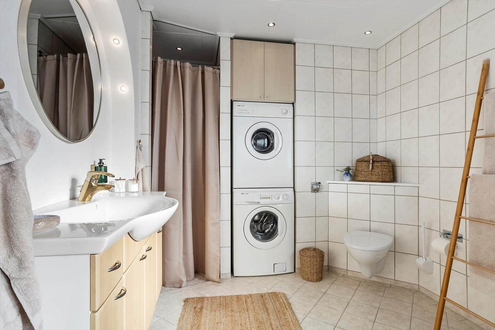Badezimmer mit Waschmaschine, Spiegelschrank und Duschvorhang.