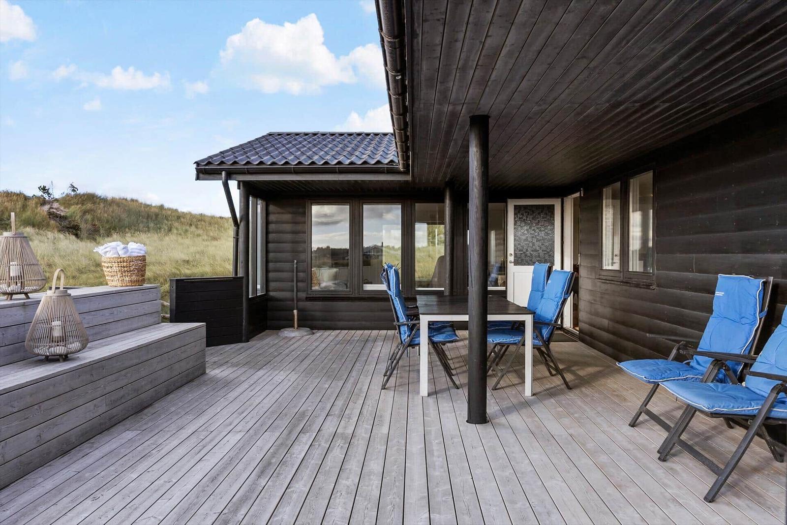 Terrasse mit Tisch, blauen Stühlen und Blick auf Grasland.