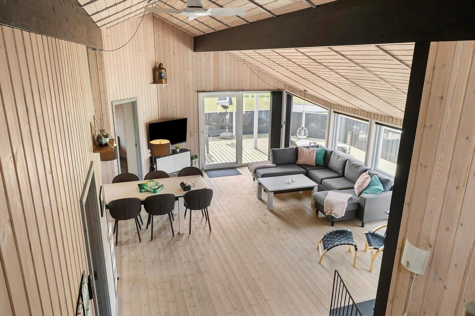 Wohn- und Essbereich mit Holzdecke, Sofa, Tisch und Stühle. Blick auf Terrasse.