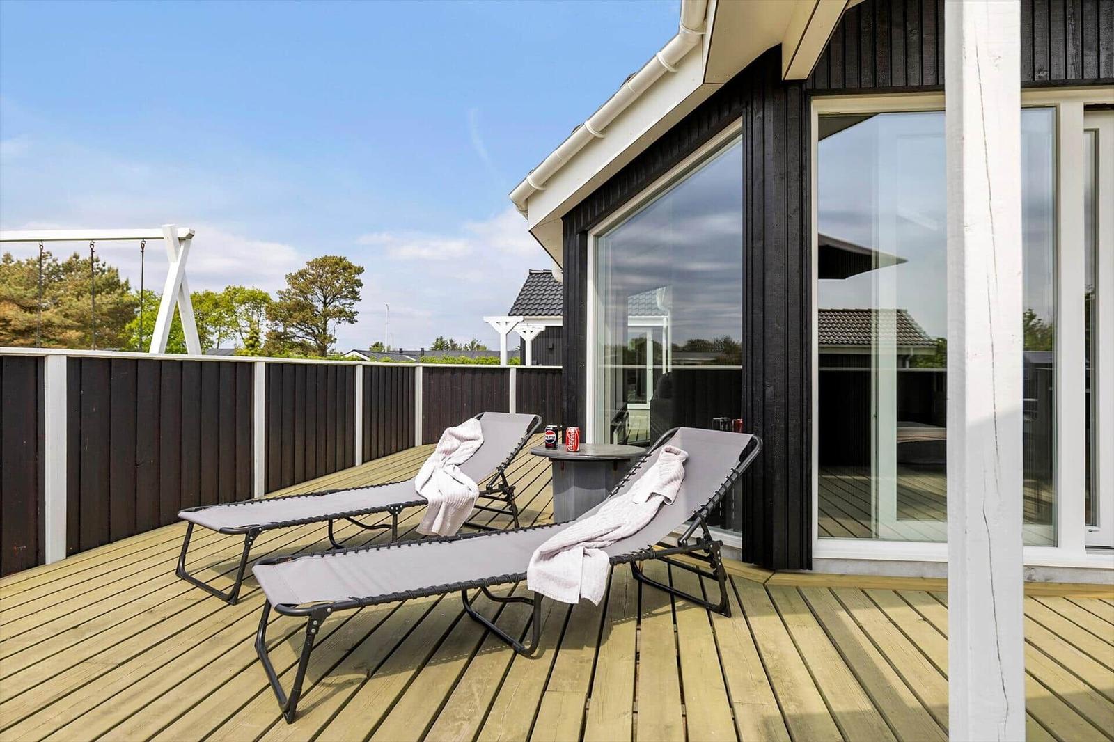 Terrasse mit zwei Liegen, Tisch und Blick auf die Umgebung.