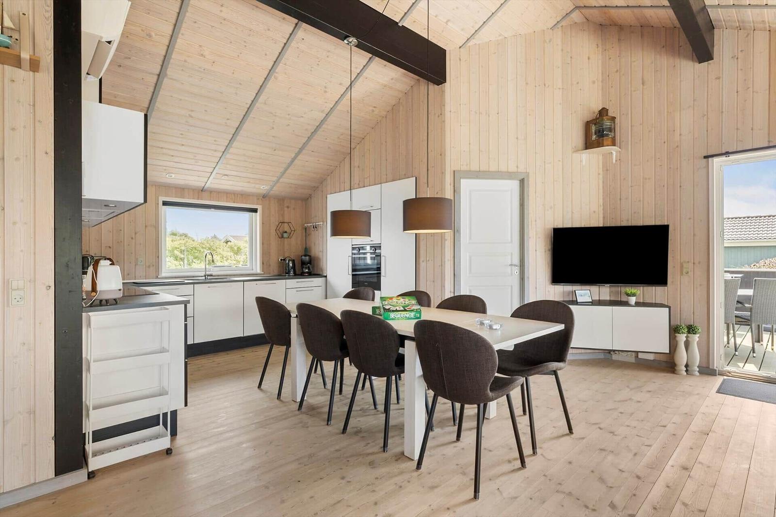 Küche mit Essbereich, TV und Terrasse. Holzwände und -boden.