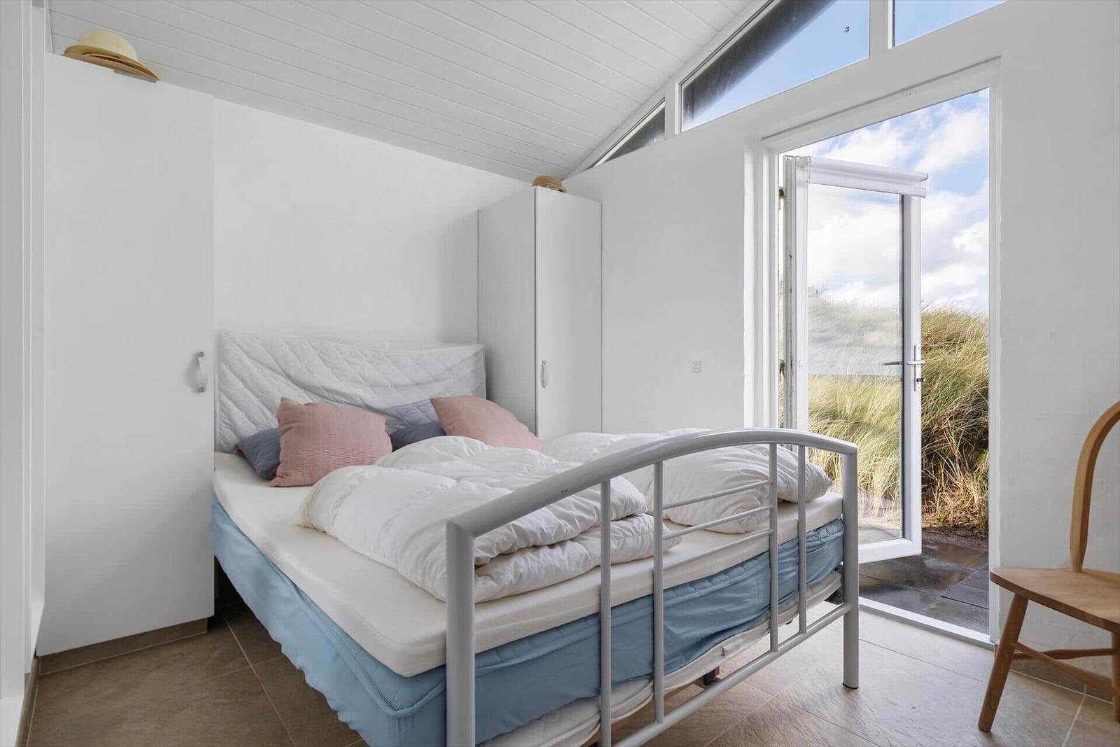 Schlafzimmer mit Bett, Schrank und Tür zum Garten.