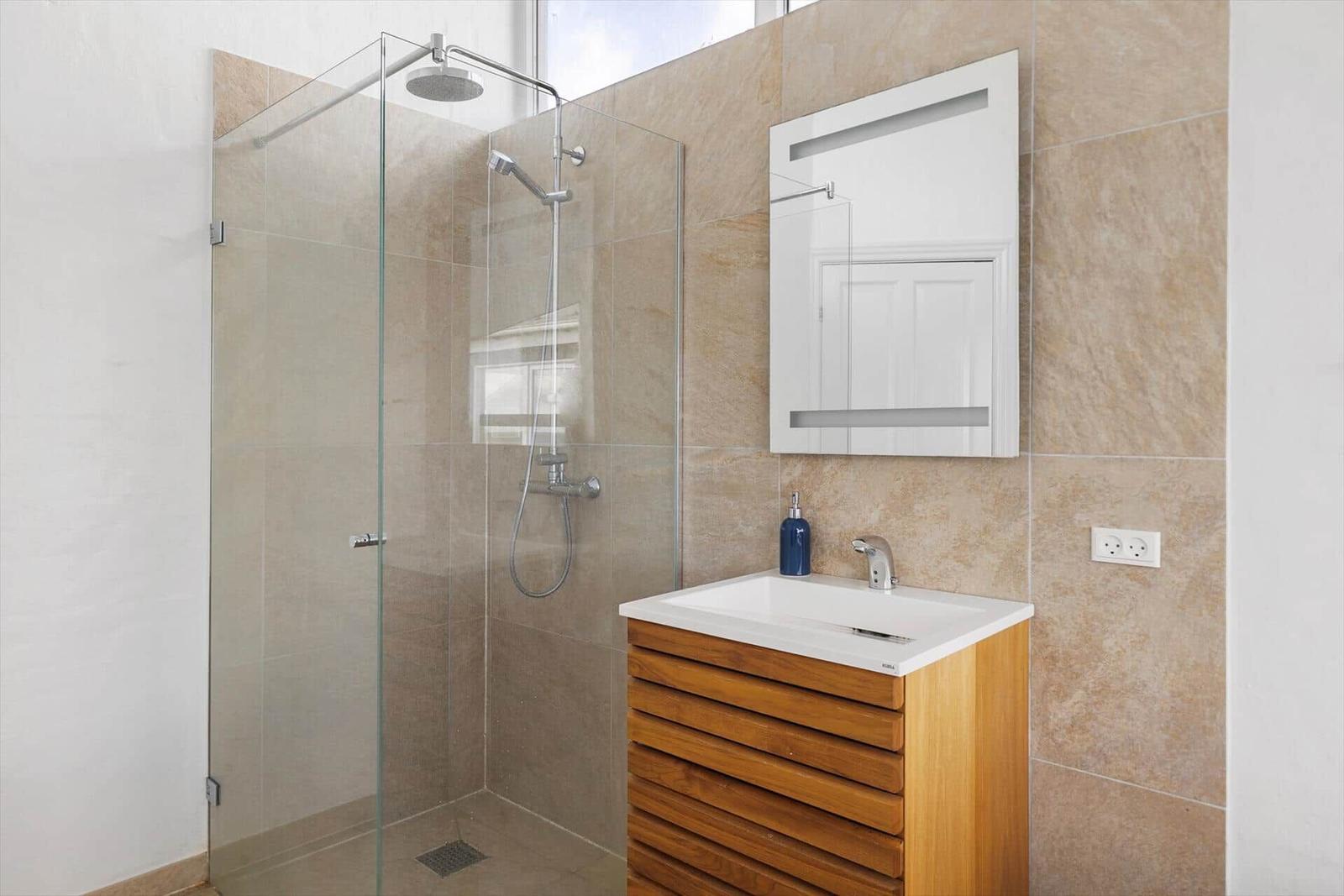 Badezimmer mit Duschkabine, Waschbecken und Spiegel