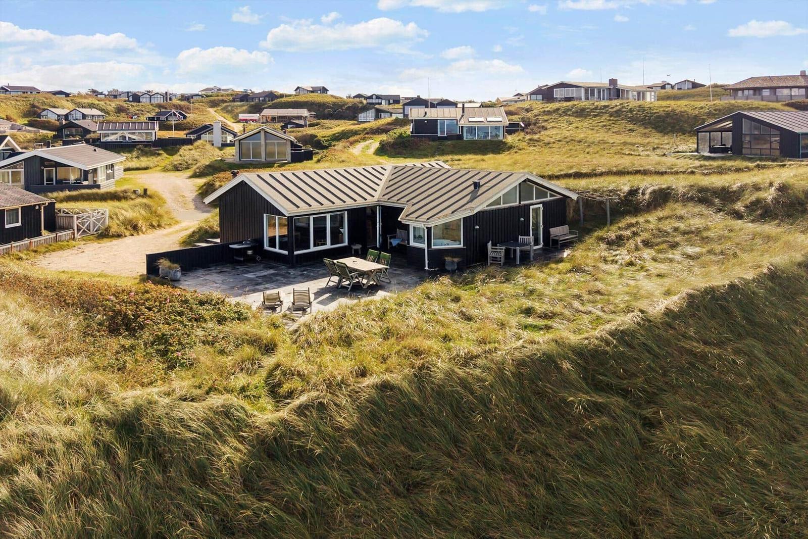 Moderne Strandvilla mit Terrasse und Garten. Blick auf die Dünen und Nachbarhäuser.
