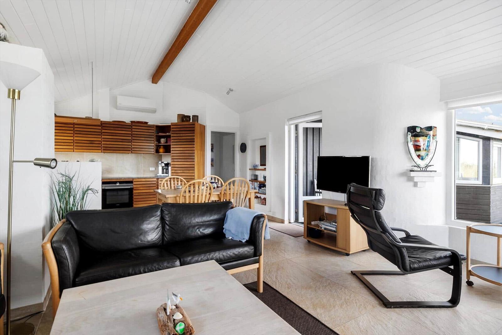 Wohnzimmer mit Sofa, Fernseher und Küchenbereich im Hintergrund.
