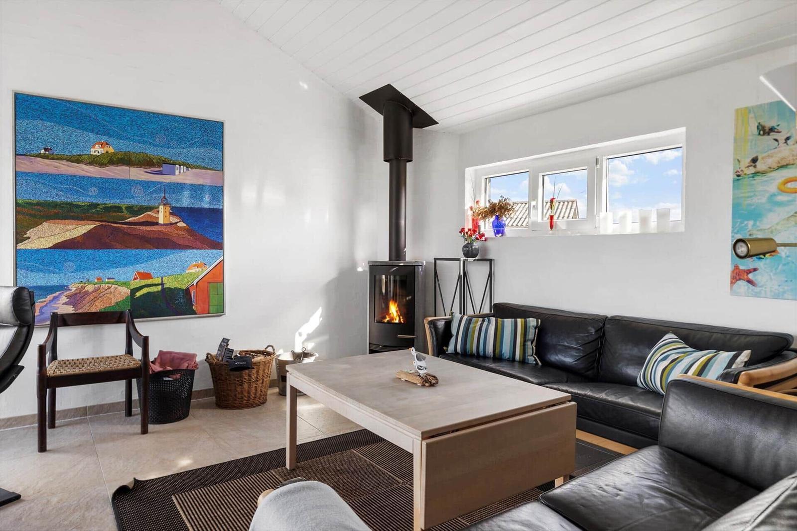 Wohnzimmer mit Sofa, Kamin und Fenster. Wandbild und Tisch sind sichtbar.