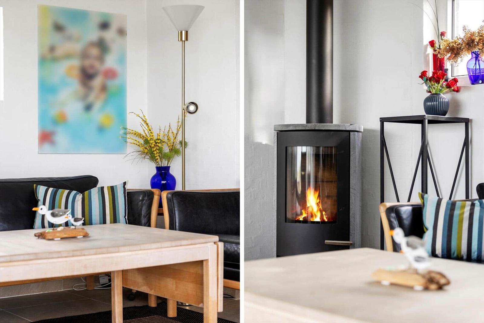 Wohnzimmer mit Kamin, Sofa und Tisch. Wandbild und Blumenvase sind sichtbar.