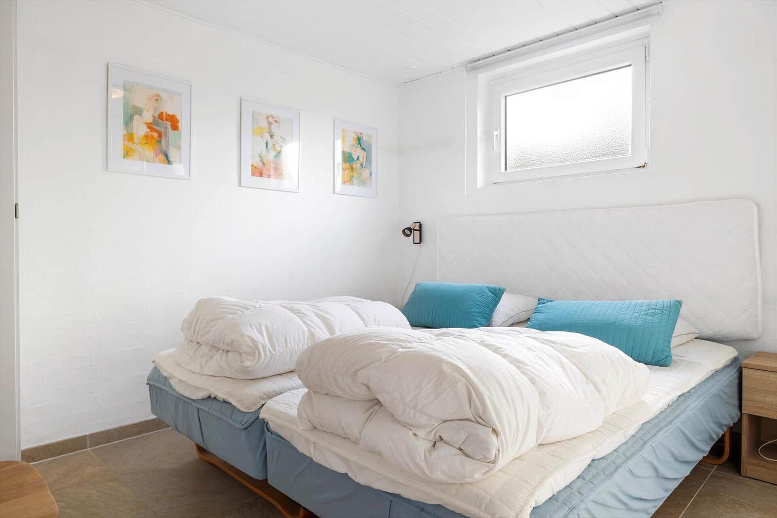 Schlafzimmer mit Bett, Wandbildern und Fenster