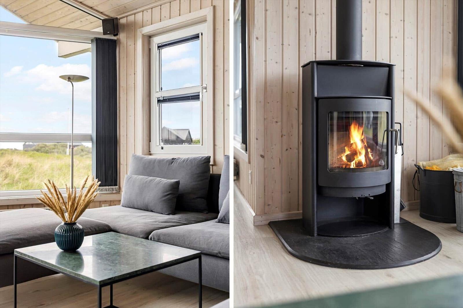 Wohnbereich mit Sofa und Kaminofen. Holzwände und großes Fenster.