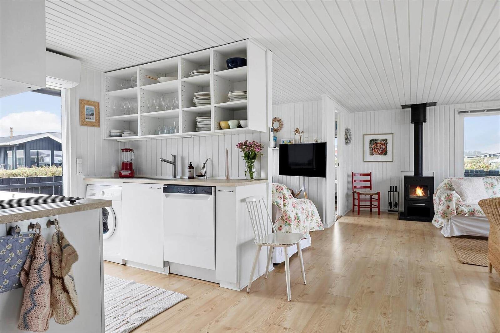 Küche mit Spüle, Geschirr und Waschmaschine. Wohnbereich mit Kamin und Sofa.