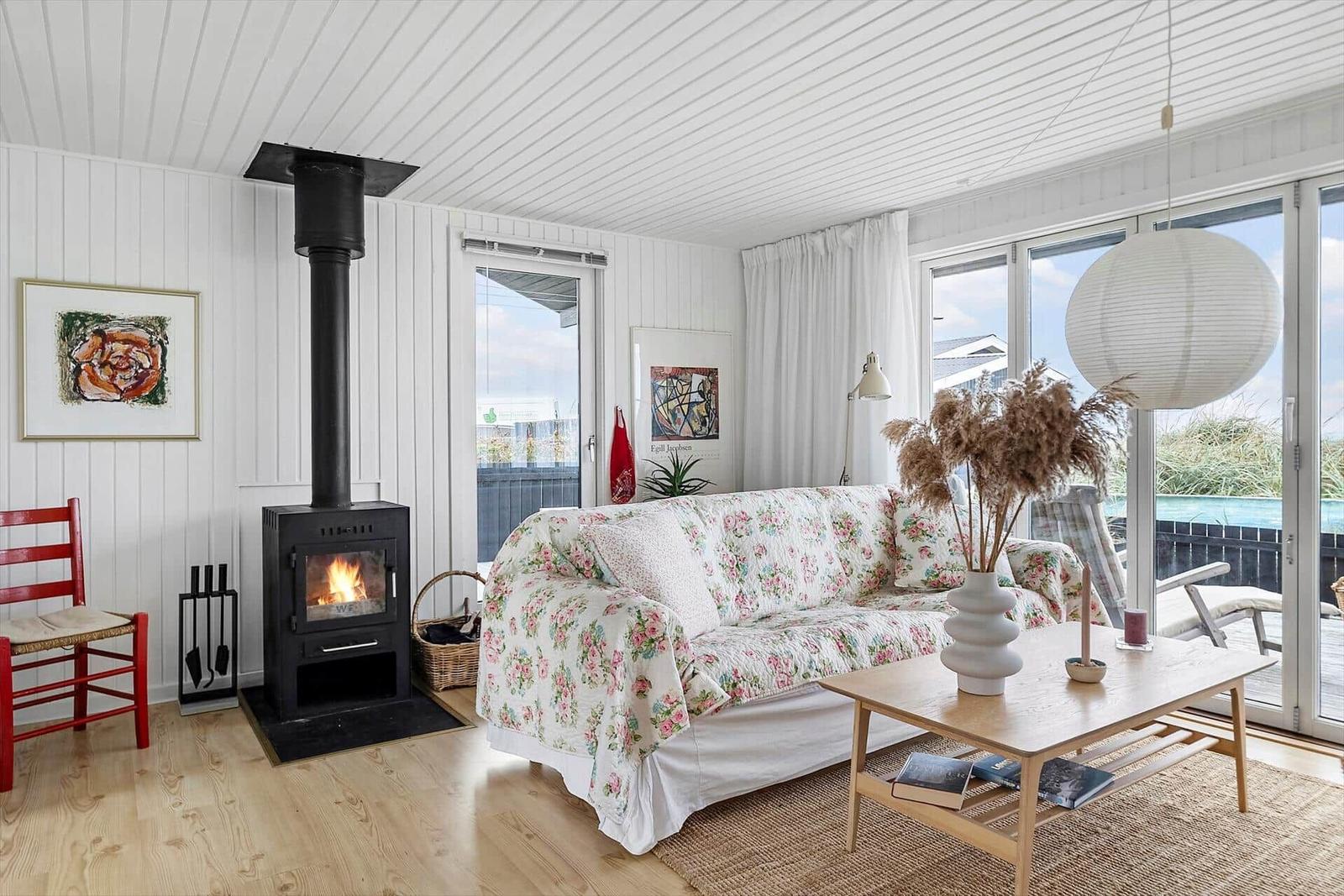 Wohnzimmer mit Kamin, Sofa mit Blumenbezug und Holztisch.