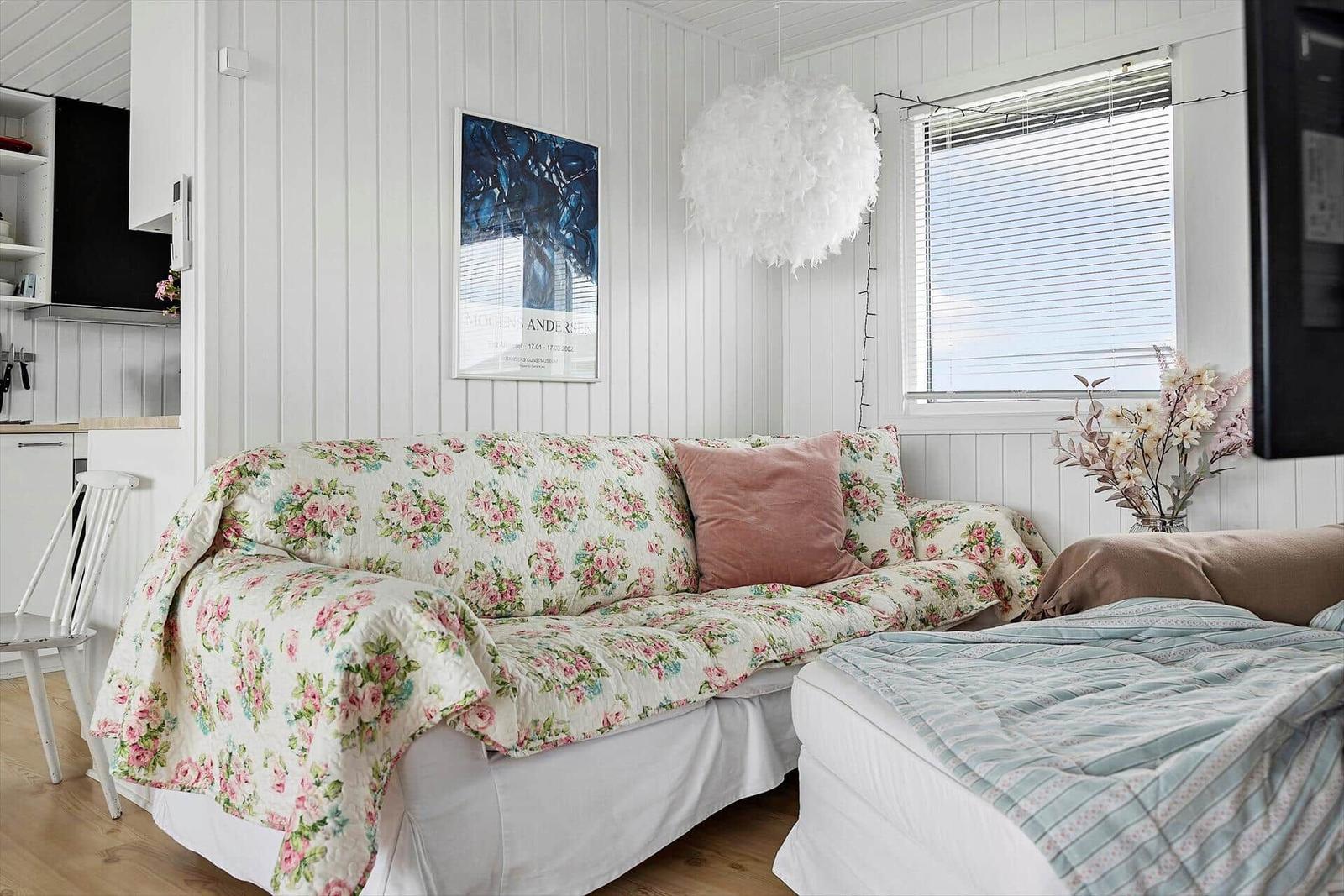 Wohnbereich mit Sofa, Bett und Fenster. Wandgestaltung mit Bild und Pendelleuchte.