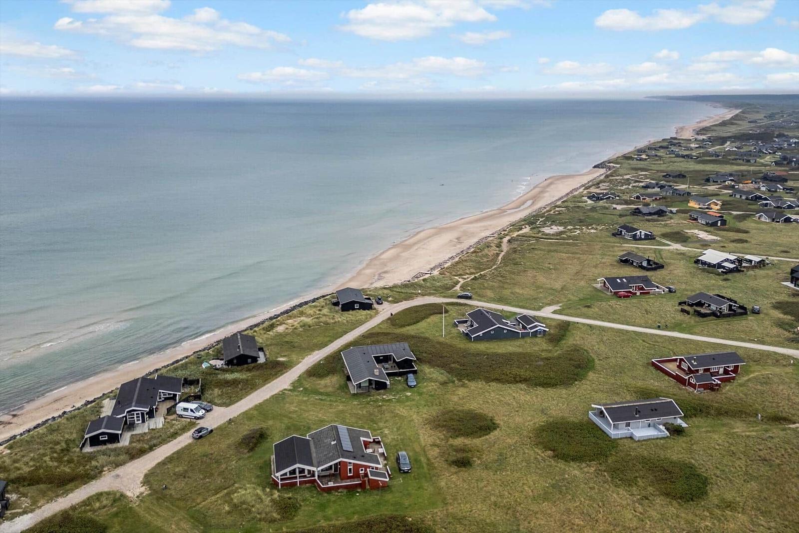 Aerielansicht von Strandhäusern entlang einer Küstenstraße.
