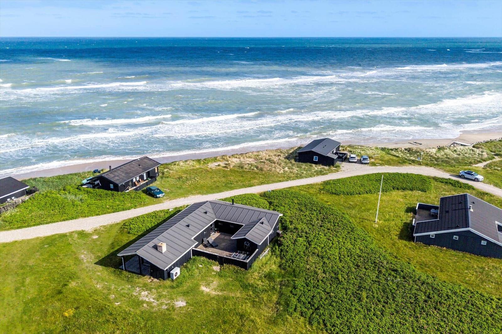 Strandnahe Ferienhäuser mit Grünflächen und Meerblick.