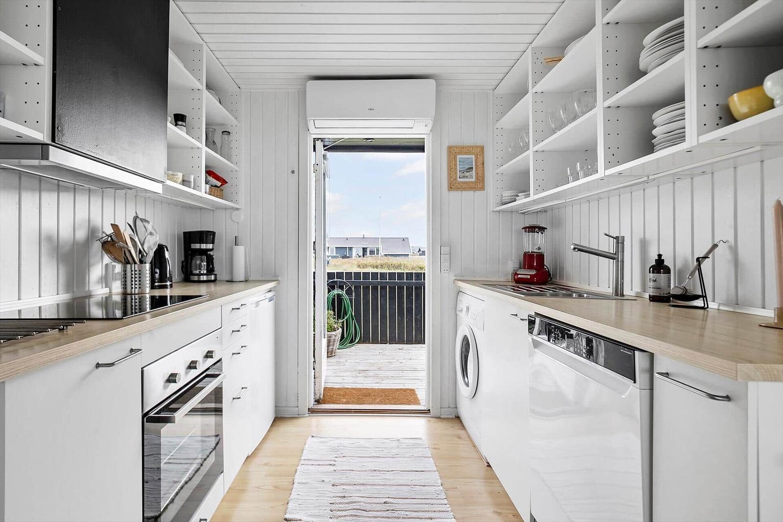 Küche mit weißer Einbauküche, Holzoberflächen und Blick auf Balkon