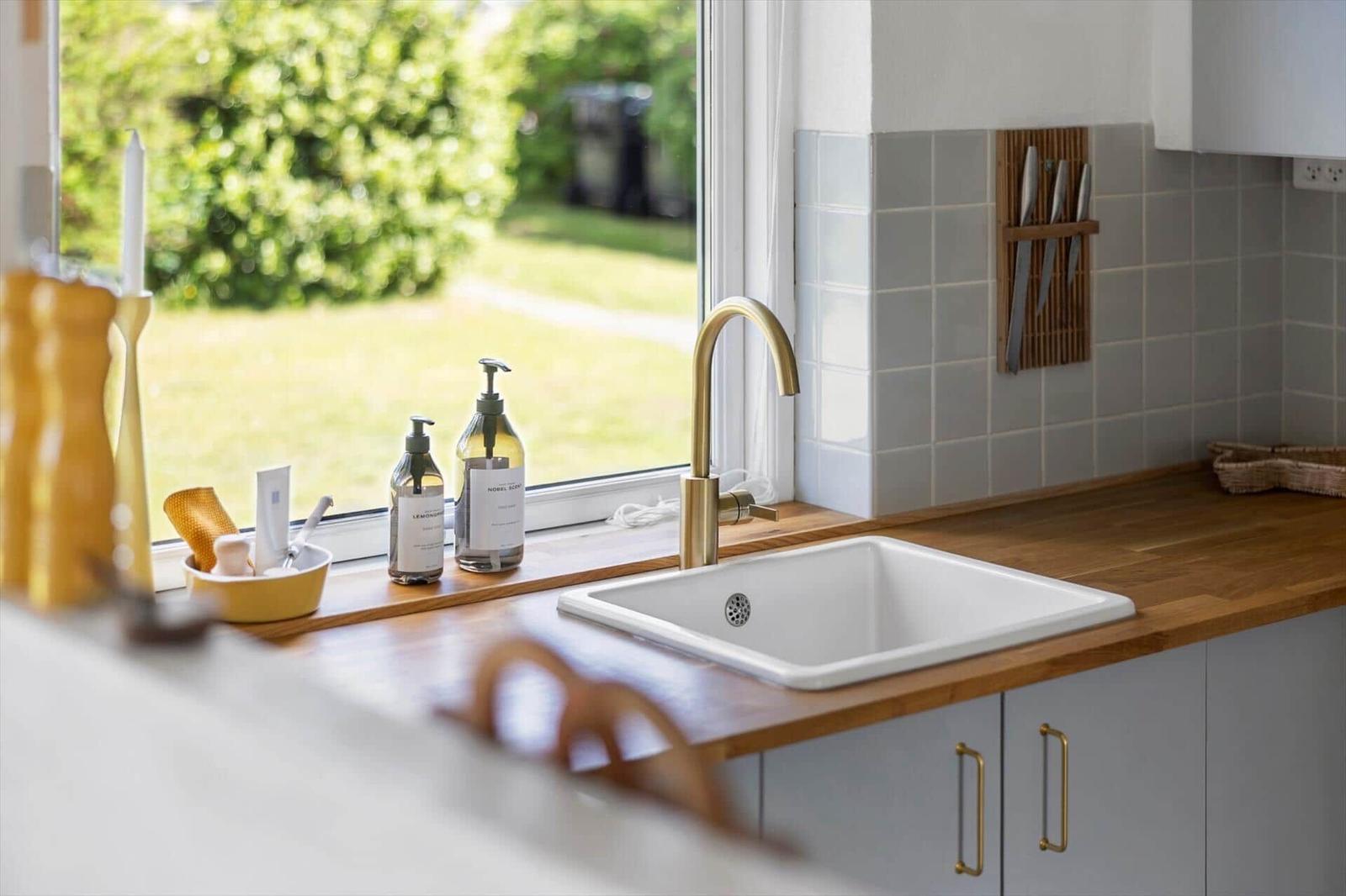 Küchenarbeitsfläche mit Waschbecken und Fensterblick auf Grünfläche.