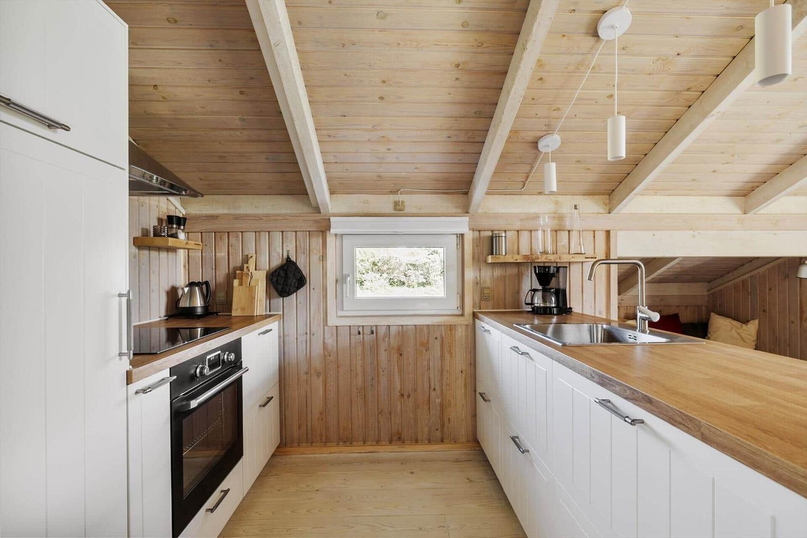 Küche mit Holzwand, weißen Schränken und Holz Arbeitsplatte.