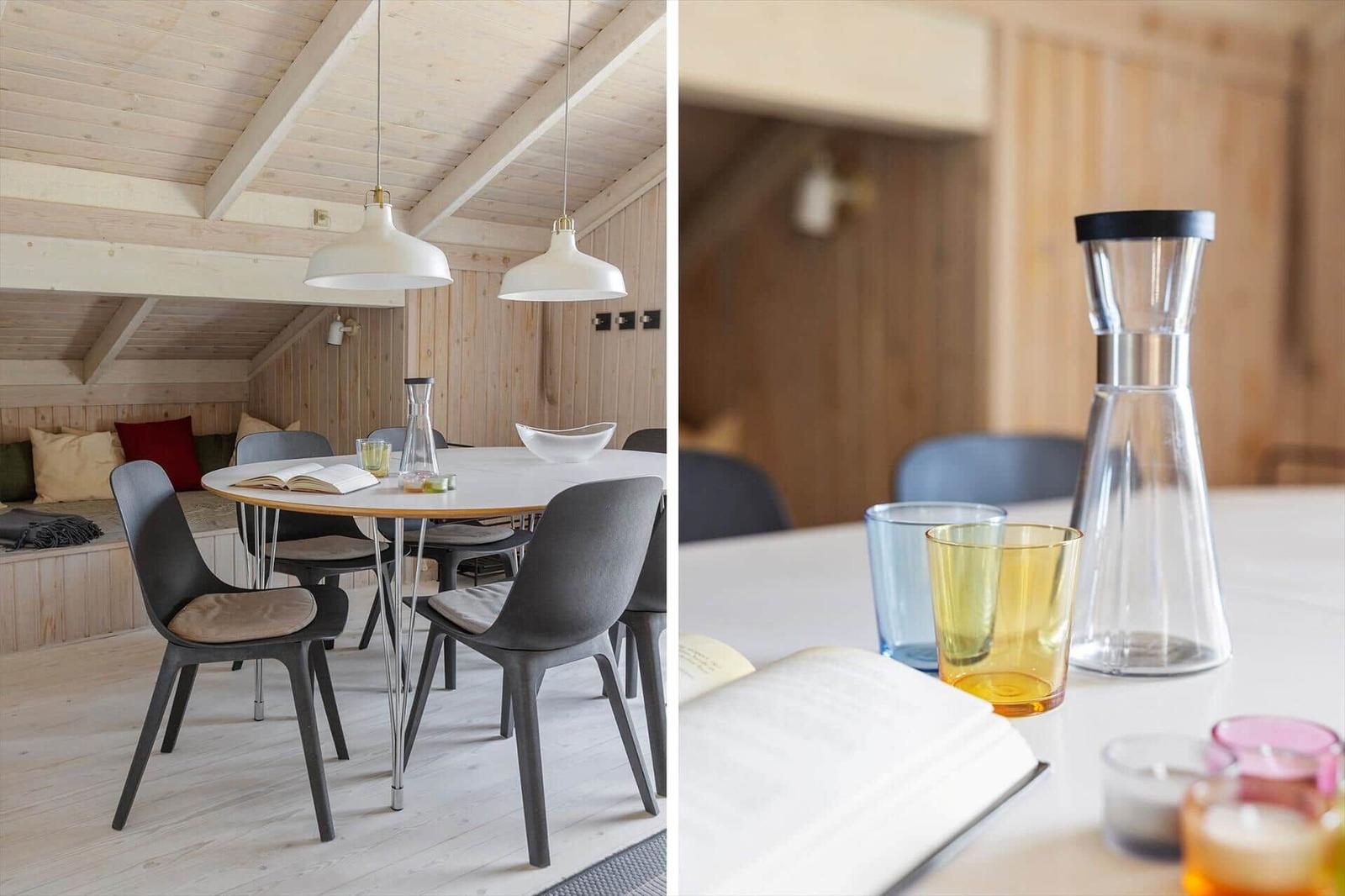 Esszimmer mit Holzdecke, runden Tisch und Stühlen. Auf dem Tisch stehen Gläser und eine Karaffe.