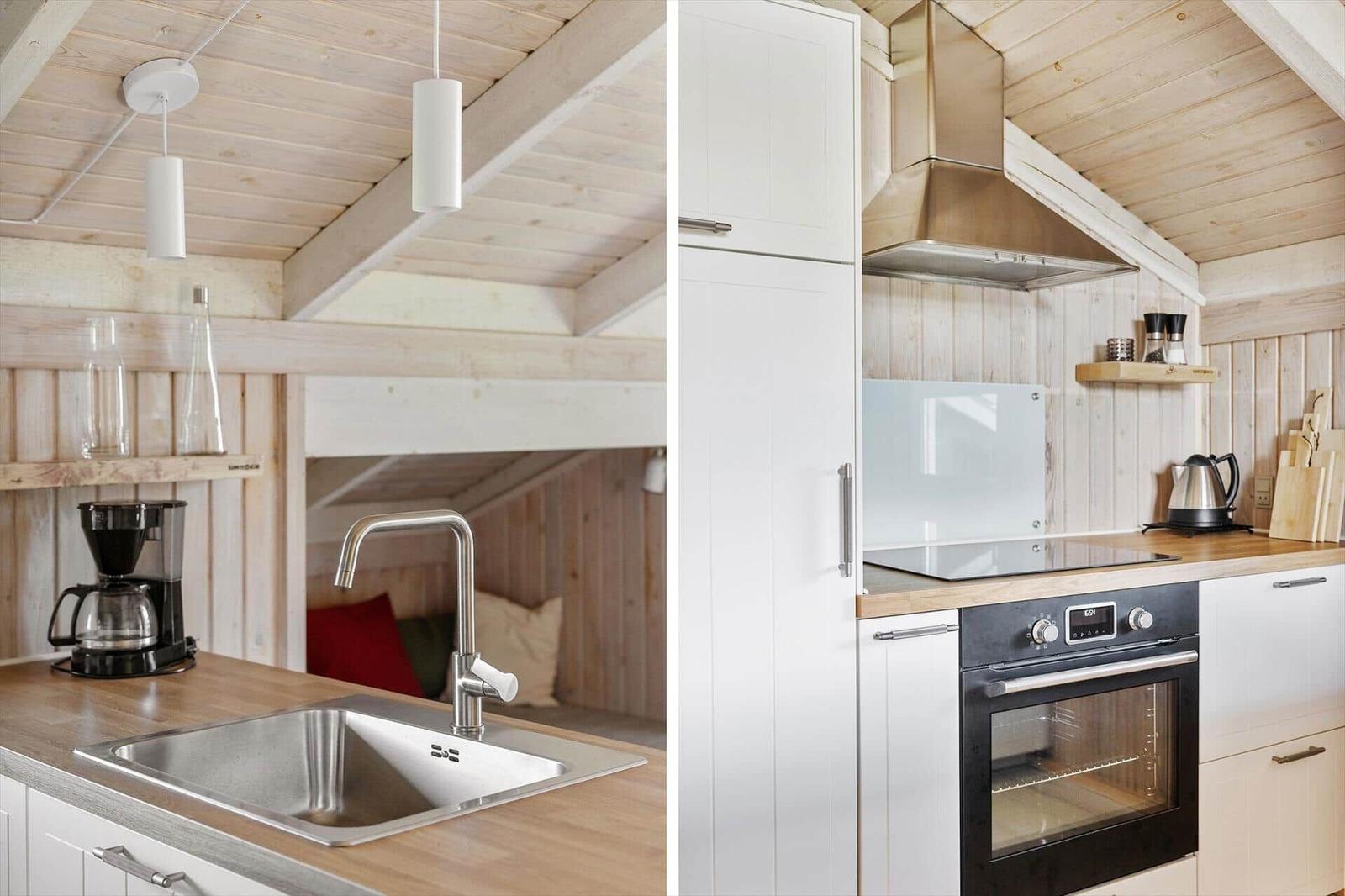 Küche mit Spüle, Kaffeemaschine und Ofen unter Holzdecke.