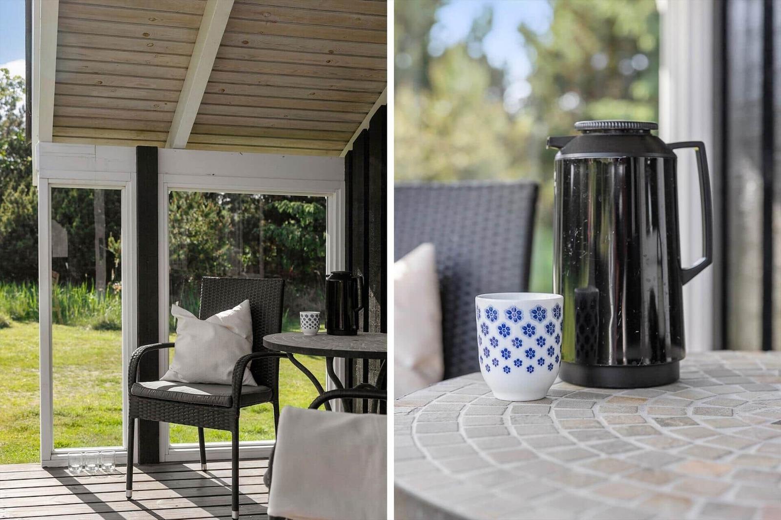 Terrasse mit Sitzgelegenheit und Tisch. Auf dem Tisch steht eine Tasse und eine Kanne.