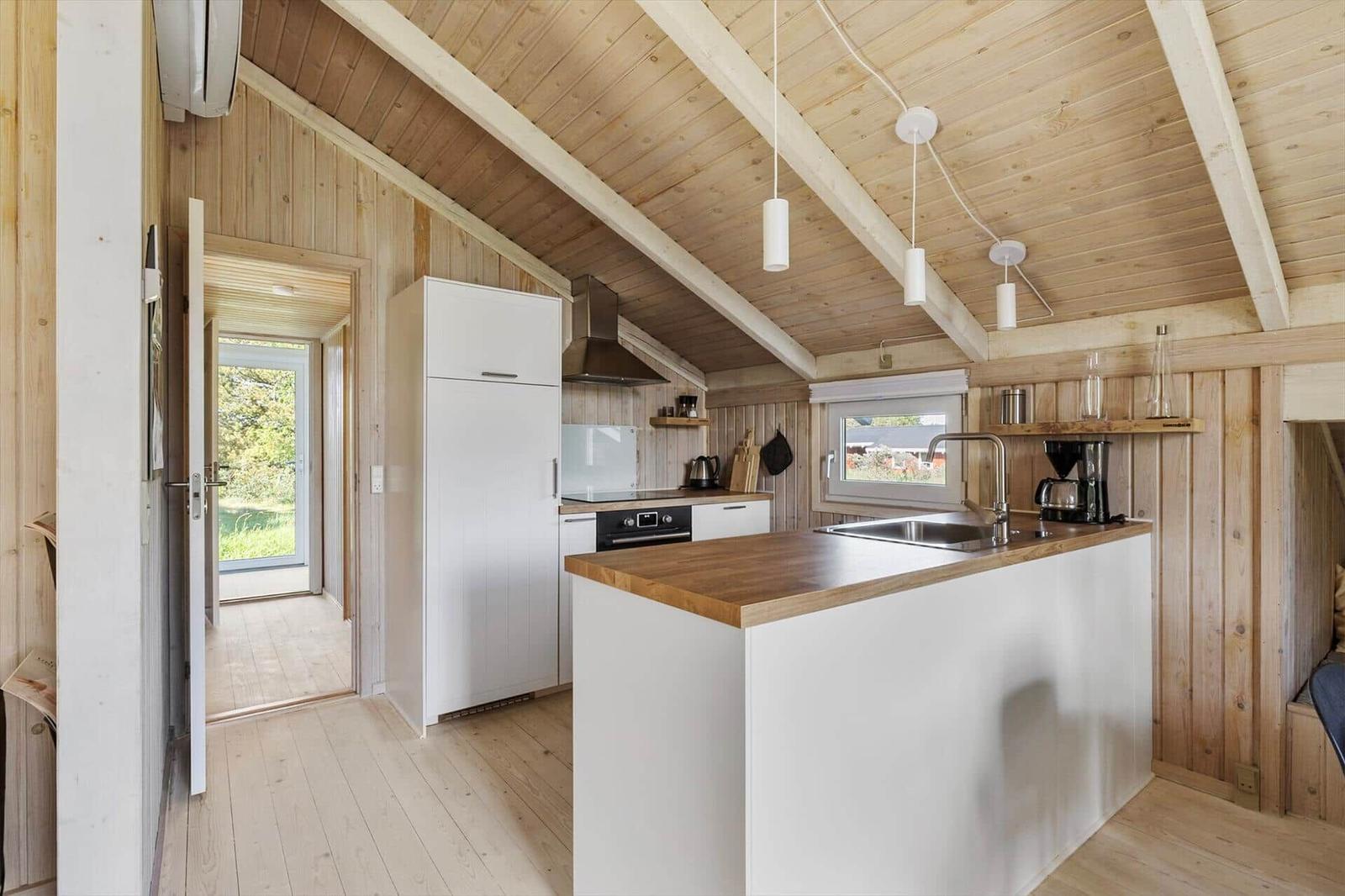Küche mit Holzdecke, weißer Arbeitsfläche und Kücheninsel.