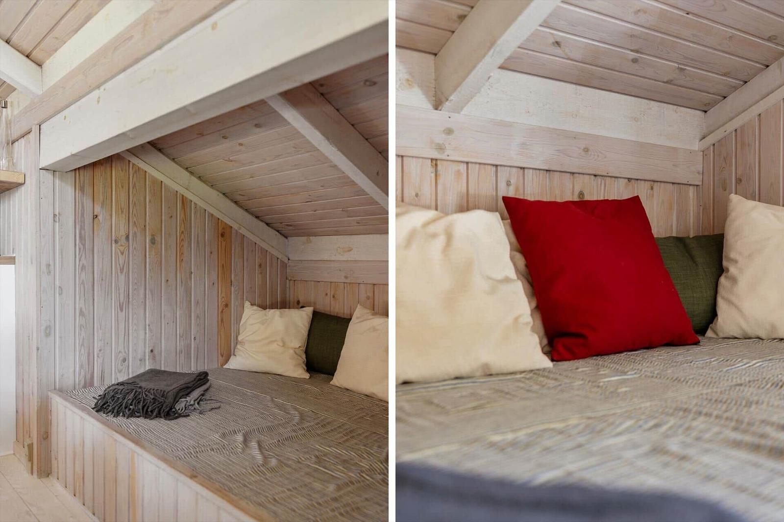 Ein Bett unter einem Holzdach mit Kissen und einer Decke.