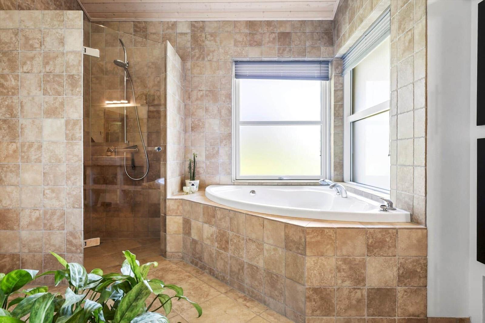 Bad mit Dusche und Whirlpool-Badewanne, Wandfliesen und Fenstern.