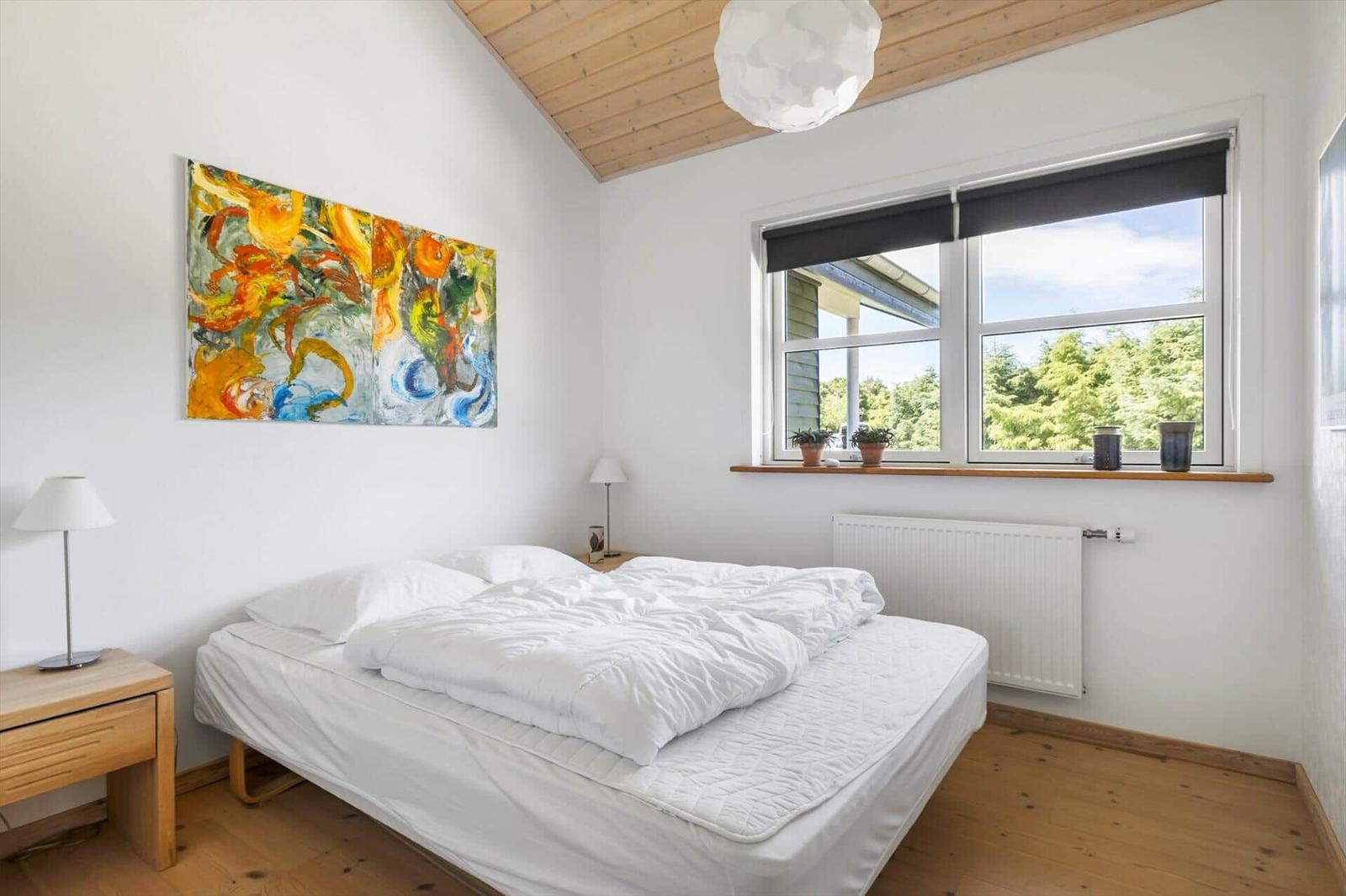 Schlafzimmer mit Bett, Fenster und Wandbild