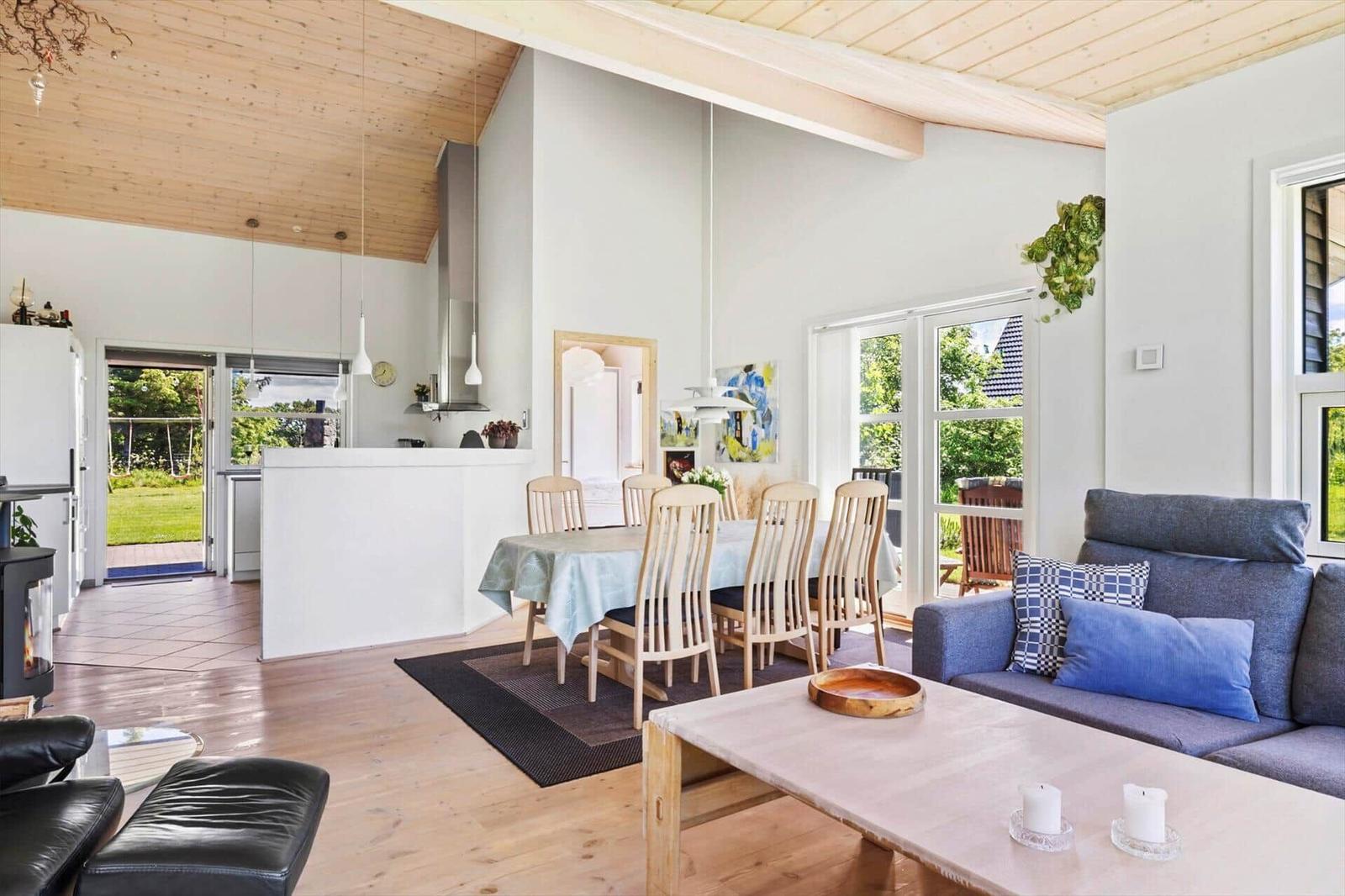 Wohn- und Essbereich mit Holzboden, Sofa und Esstisch. Durchgang zur Küche und Garten.