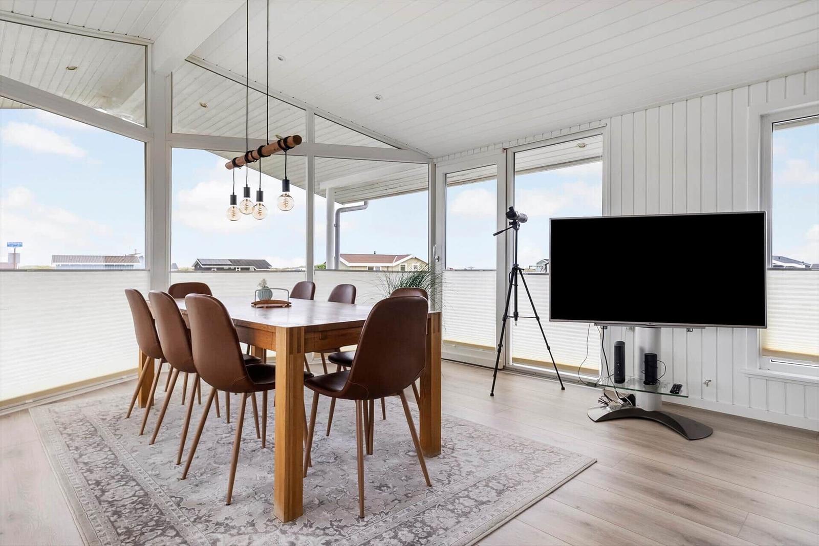Esszimmer mit Holztisch, braunen Stühlen und Fernseher an der Wand.