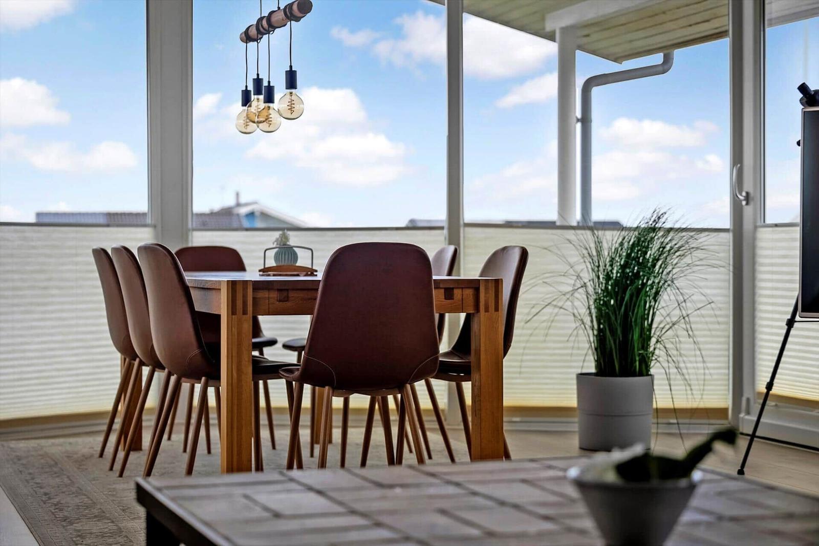 Esszimmer mit Holztisch, Stühlen und Blick auf den Balkon.