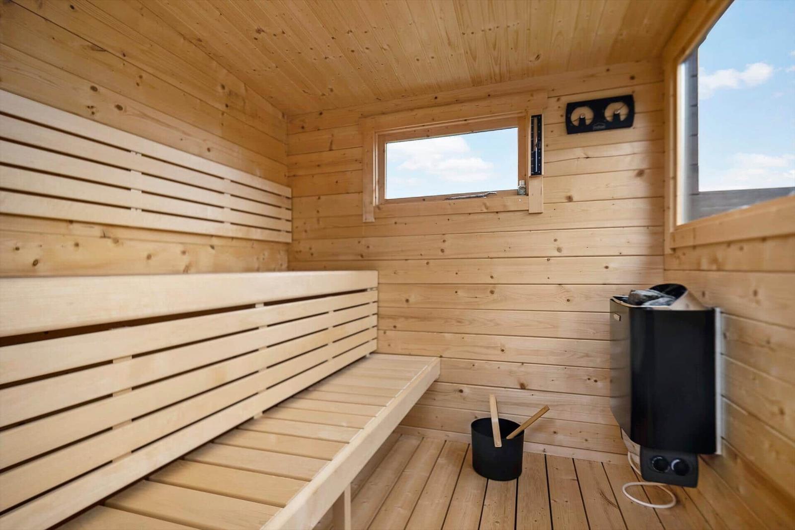 Sauna mit Holzbank, Heizung und Fenster zum Blick nach draußen.