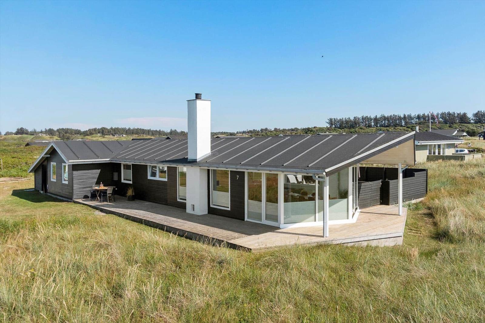 Moderne Ferienhaus mit Terrasse und großem Fensterbereich in ländlicher Umgebung.
