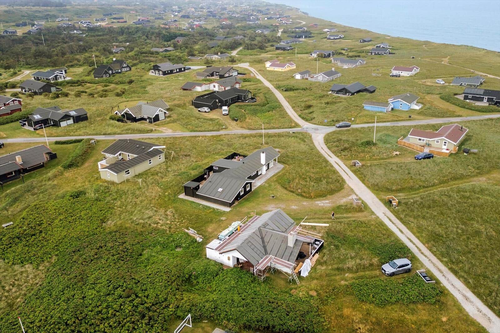 Aerial view of coastal village with houses and roads near water.